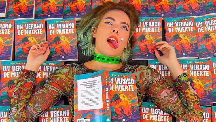 Xuri Fenton posa de forma cómica junto a algunos ejemplares de su libro