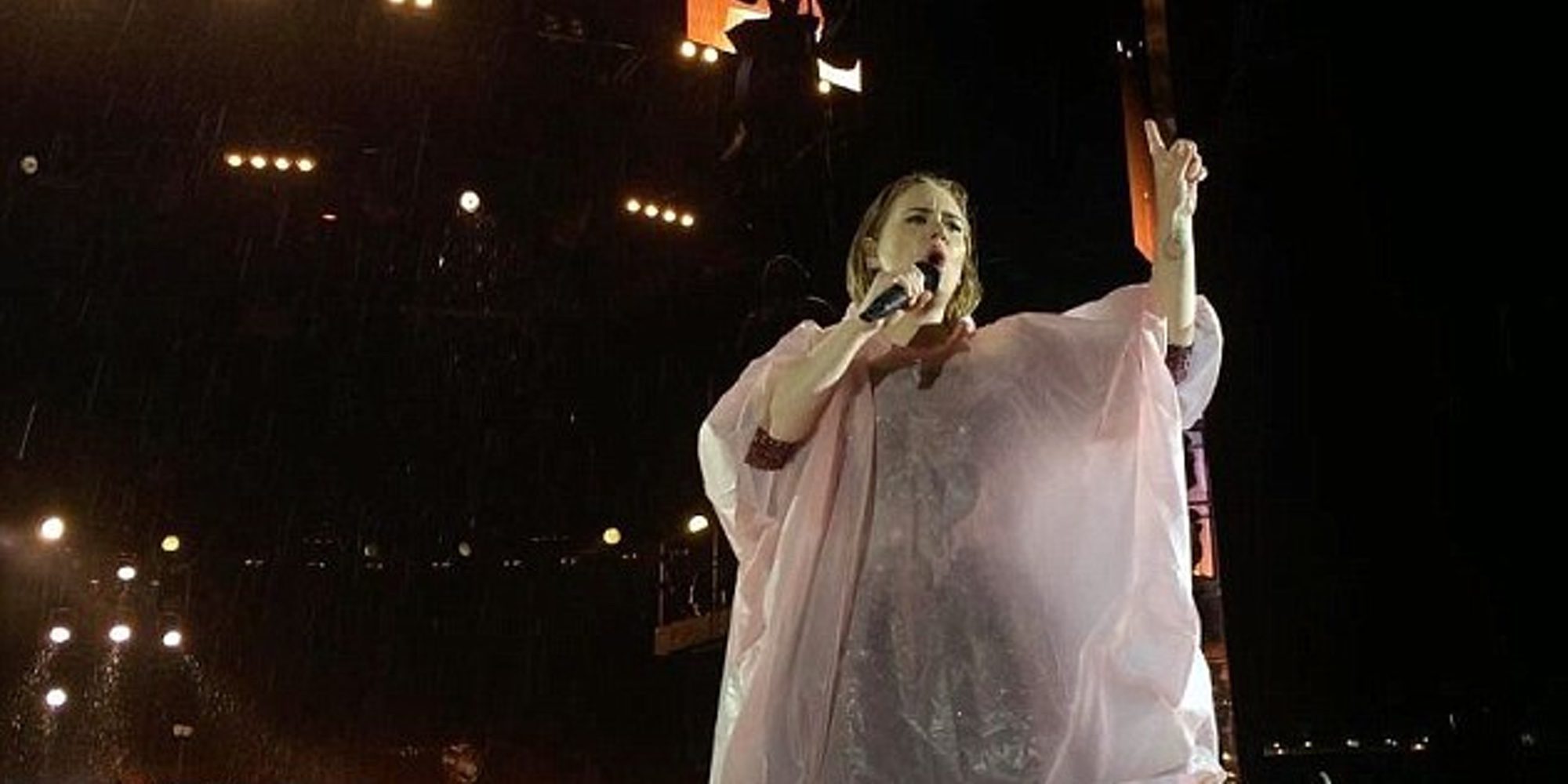 Adele se protege de una increíble tormenta durante un concierto con un poncho rosa de plástico