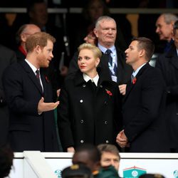 El Príncipe Harry charlando con Charlene de Mónaco y Gareth Wittstock en un partido de rugby