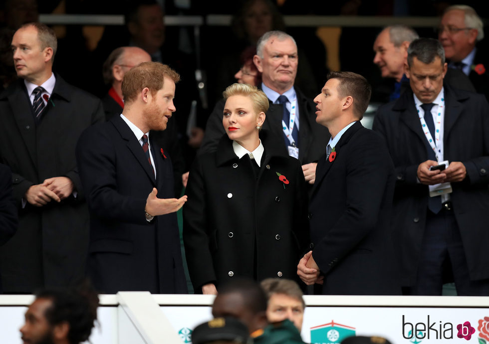 El Príncipe Harry charlando con Charlene de Mónaco y Gareth Wittstock en un partido de rugby