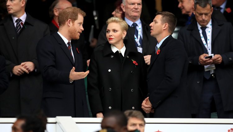 El Príncipe Harry charlando con Charlene de Mónaco y Gareth Wittstock en un partido de rugby