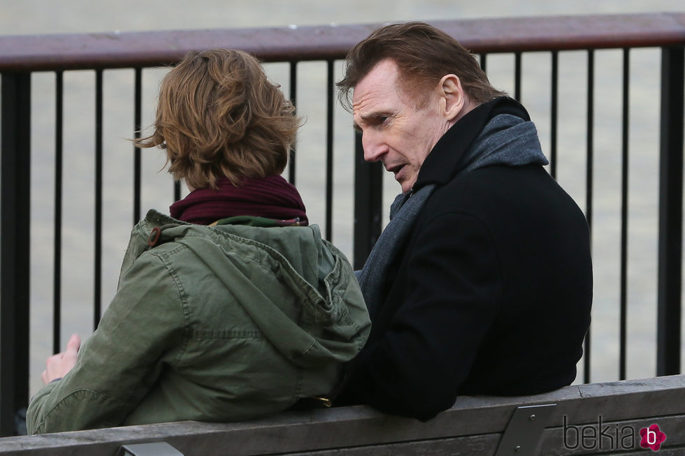 Liam Neeson y Thomas Brodie Sangster sentados en un banco en una de las secuencias de 'Love Actually 2'