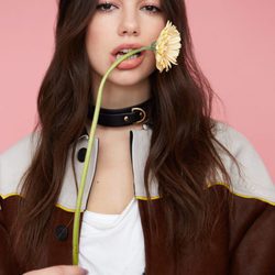 Dua Lipa posando con una flor en la boca