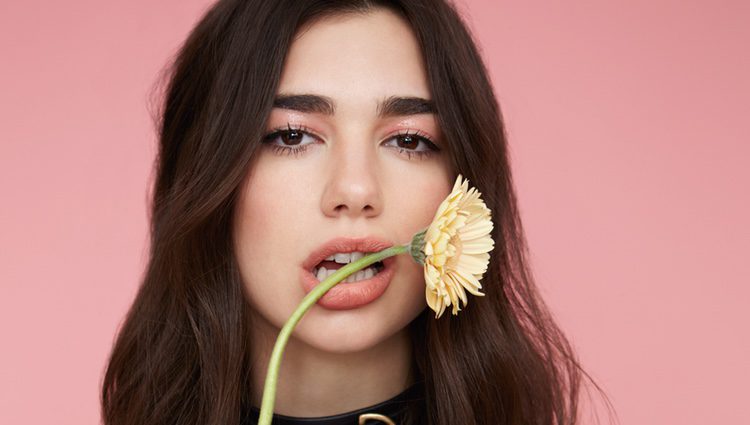 Dua Lipa posando con una flor en la boca