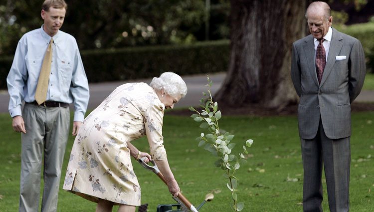 La Reina Isabel planta un árbol mientras el Duque de Edimburgo le observa