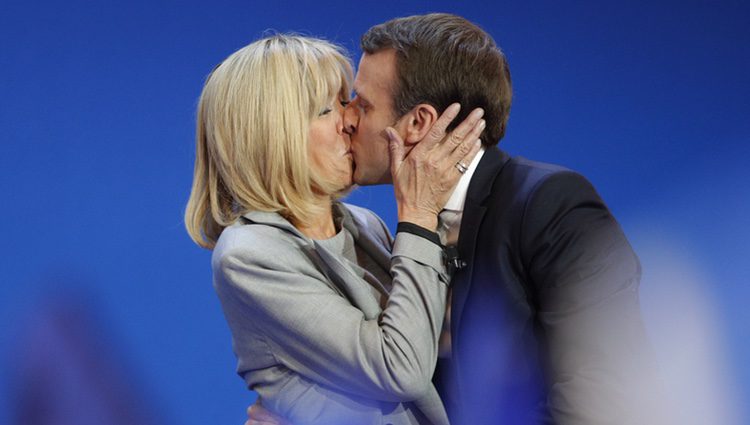 Emmanuel y Brigitte Macron besándose en una acto público