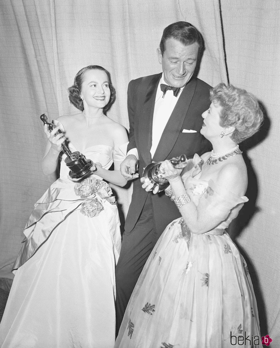 Olivia de Havilland recogiendo su Oscar junto a John Wayne