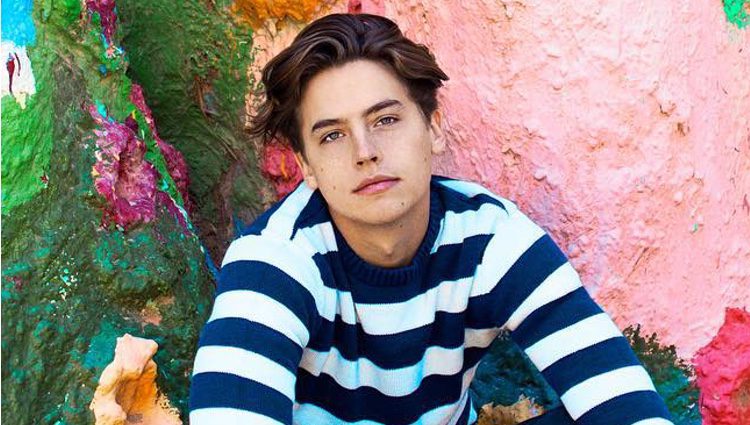 Cole Sprouse posando en una pared coloreada