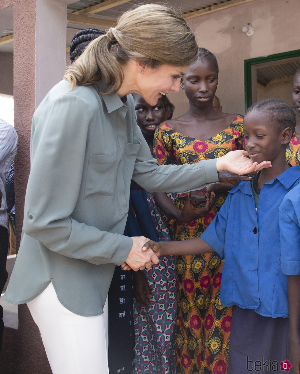 La Reina Letizia con un niño en la granja Naatangué de Senegal