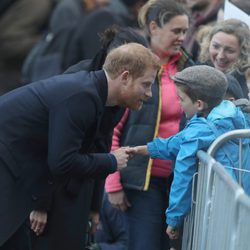 El Príncipe Harry saluda a un niño durante su visita oficial a Gales con Meghan Markle