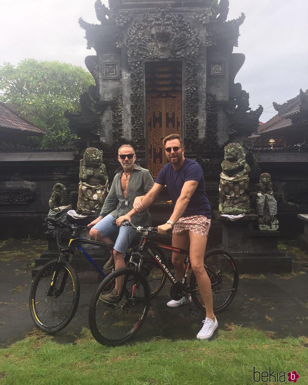 Joaquín Torres y Raúl Prieto en un lugar paradisíaco montados en una bicicleta