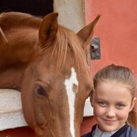 Isabel de Dinamarca sonriente junto a un caballo en su onceavo cumpleaños