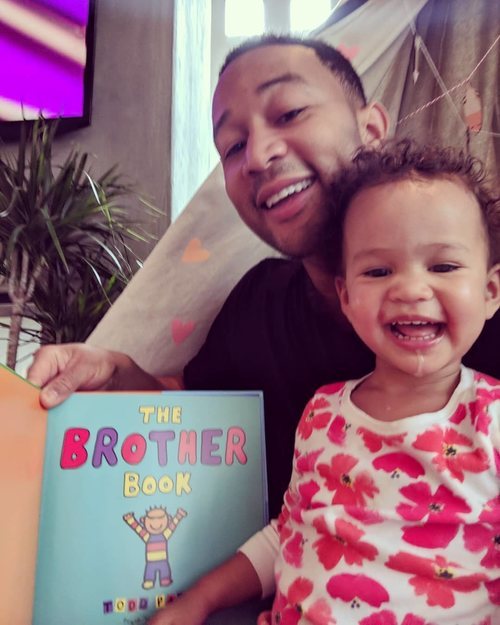 John Legend junto a su hija Luna leyendo un libro