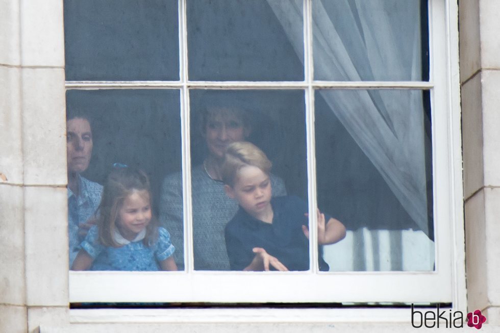 El Príncipe Jorge y la Princesa Carlota con su niñera mirando por una ventana de Buckingham Palace