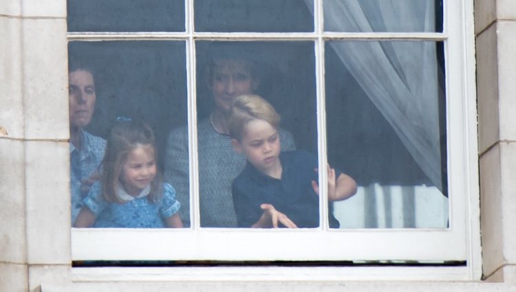 El Príncipe Jorge y la Princesa Carlota con su niñera mirando por una ventana de Buckingham Palace