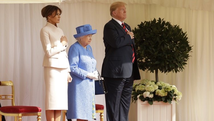 Los Trump con la mano en el corazón junto a la Reina Isabel II