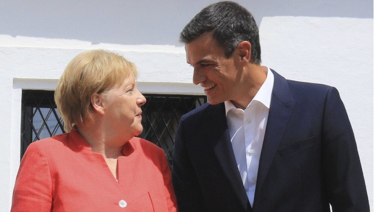 Pedro Sánchez y Angela Merkel se miran sonrientes durante la visita de la canciller al Palacio de los Guzmanes