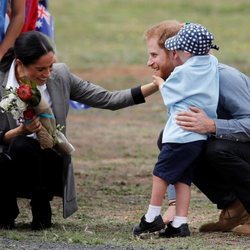 Meghan Markle ríe divertida mientras un niño toca la barba del Príncipe Harry