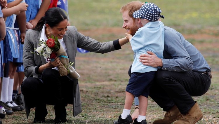 Meghan Markle ríe divertida mientras un niño toca la barba del Príncipe Harry