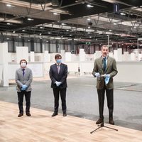 El Rey Felipe hablando con las autoridades detrás en su visita al hospital de emergencia de IFEMA