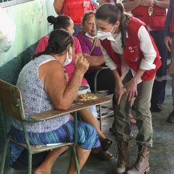 La Reina Letizia escucha el testimonio de una persona refugiada en un albergue en su viaje humanitario a Honduras