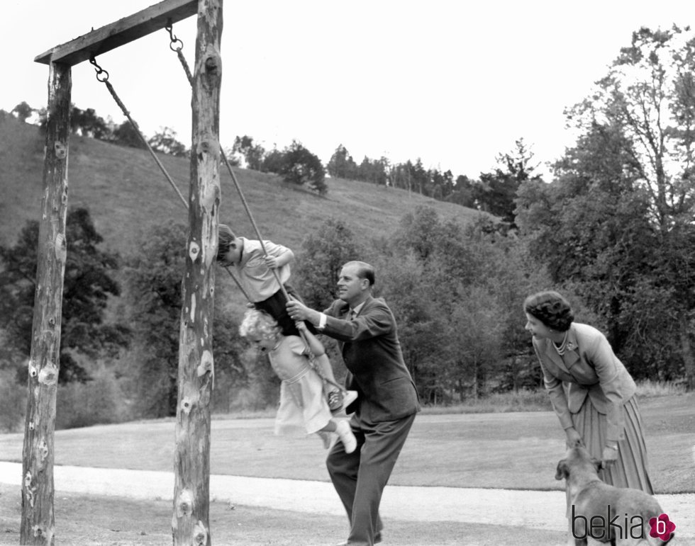 El Duque de Edimburgo columpiando al Príncipe Carlos y la Princesa Ana en presencia de la Reina Isabel en 1955