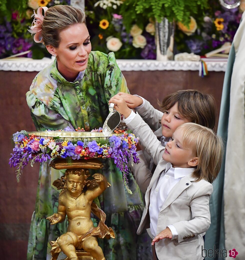 Frida Vesterberg con Alejandro y Gabriel de Suecia junto a la pila bautismal en el bautizo de Julian de Suecia