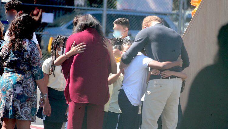 Meghan Markle y el Príncipe Harry abrazando a varios alumnos durante una visita a una escuela de Nueva York