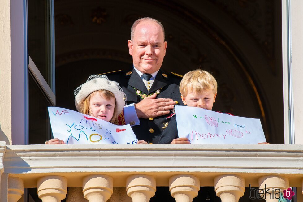 Alberto de Mónaco y Jacques y Gabriella de Mónaco con unas pancartas con un mensaje a Charlene de Mónaco en el Día Nacional de Mónaco 2021