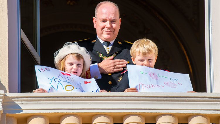 Alberto de Mónaco y Jacques y Gabriella de Mónaco con unas pancartas con un mensaje a Charlene de Mónaco en el Día Nacional de Mónaco 2021