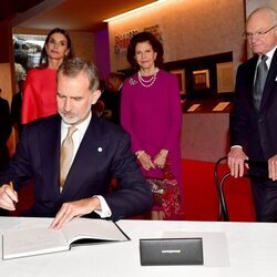 El Rey Felipe firmando en el Museo Nobel en presencia de la Reina Letizia y los Reyes de Suecia