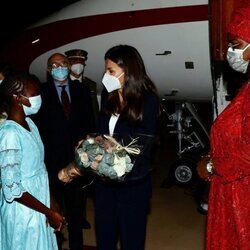 La Reina Letizia recibe un ramo de flores de manos de una niña a su llegada a Senegal