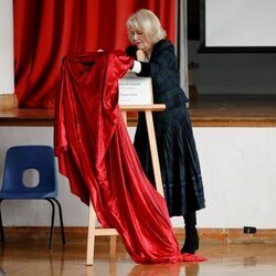 Camilla Parker tratando de retirar una tela que cubre una placa en su visita a la Escuela Roundhill de Bath