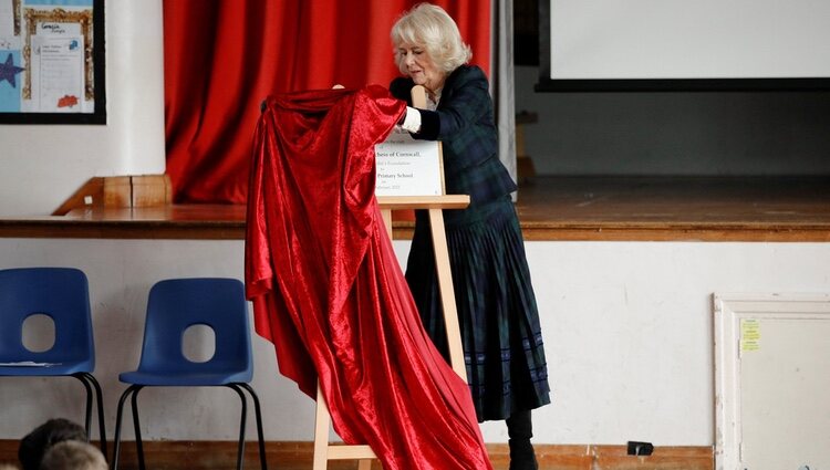 Camilla Parker tratando de retirar una tela que cubre una placa en su visita a la Escuela Roundhill de Bath