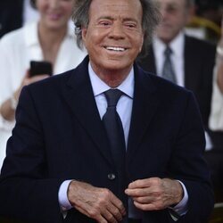 Julio Iglesias se abrocha la chaqueta durante un acto oficial