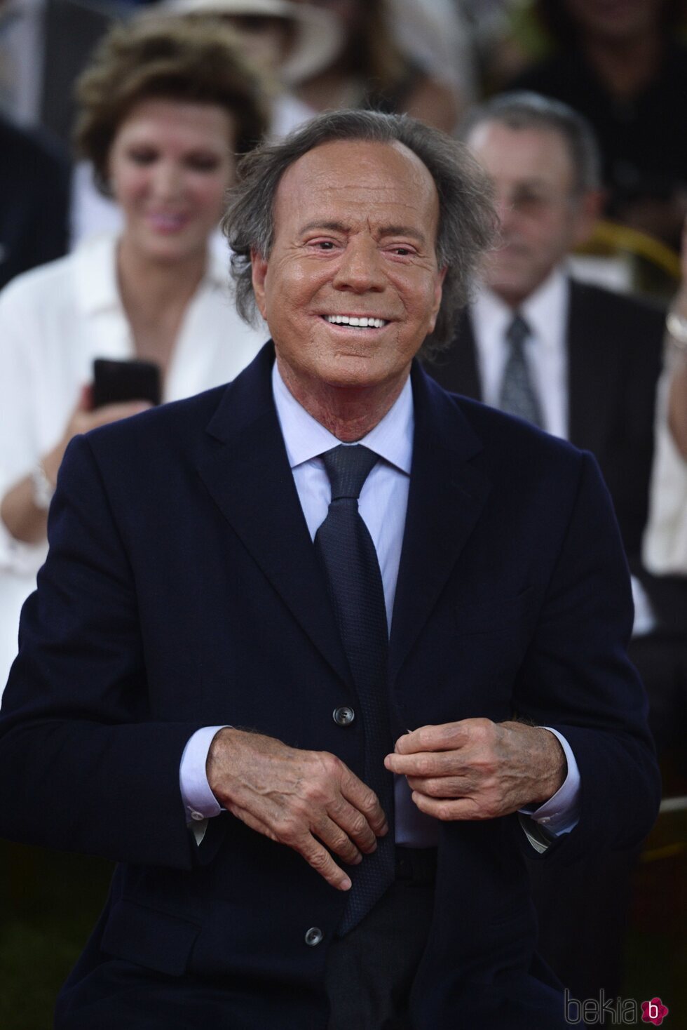 Julio Iglesias se abrocha la chaqueta durante un acto oficial