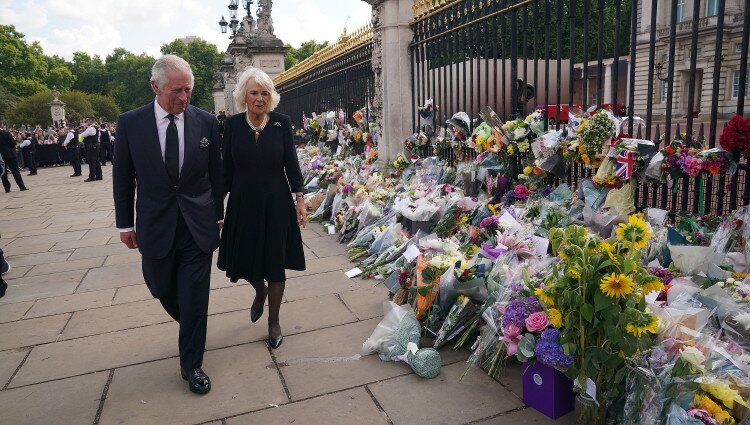 El Rey Carlos y la Reina Camilla miran las flores a las puertas del Buckingham Palace