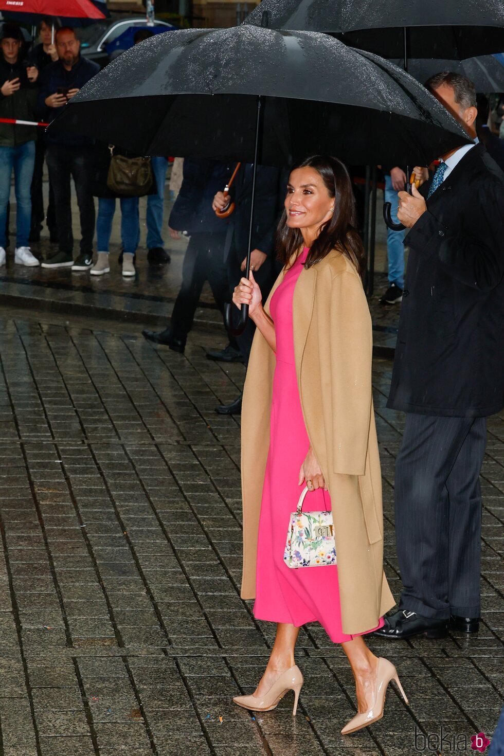 La Reina Letizia con paraguas, un vestido rosa y bolso de flores en la Puerta de Brandeburgo en la Visita de Estado de los Reyes de España a Alemania