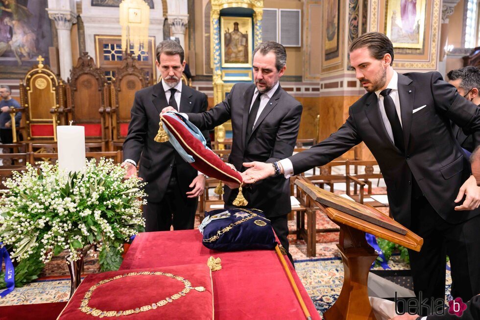 Pablo, Nicolás y Philippos de Grecia colocando las condecoraciones de Constantino de Grecia en el funeral de Constantino de Grecia