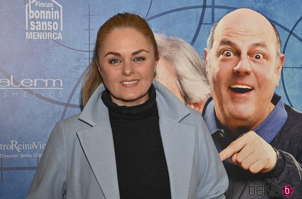 Carmen Morales posa con un abrigo azul en frente al cartel promocional del Teatro Reina Victoria