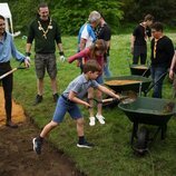 El Príncipe Louis echando tierra en una carretilla en presencia de Kate Middleton y la Princesa Charlotte en the Big Help Out por la Coronación