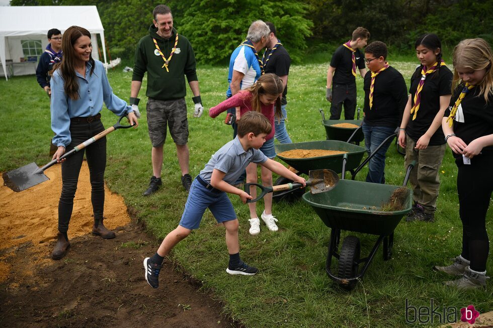 El Príncipe Louis echando tierra en una carretilla en presencia de Kate Middleton y la Princesa Charlotte en the Big Help Out por la Coronación