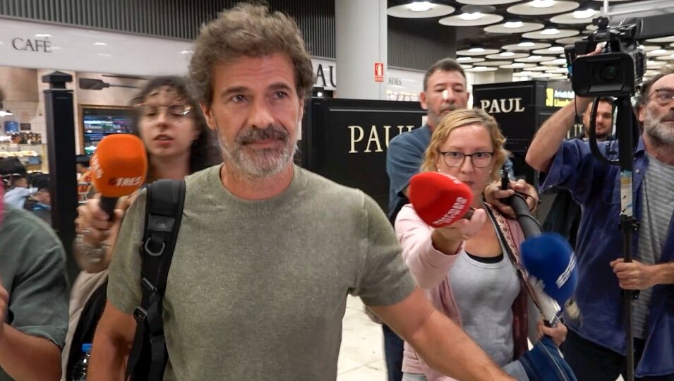 Rodolfo Sancho rodeado de prensa a su llegada a Madrid tras el viaje a Tailandia