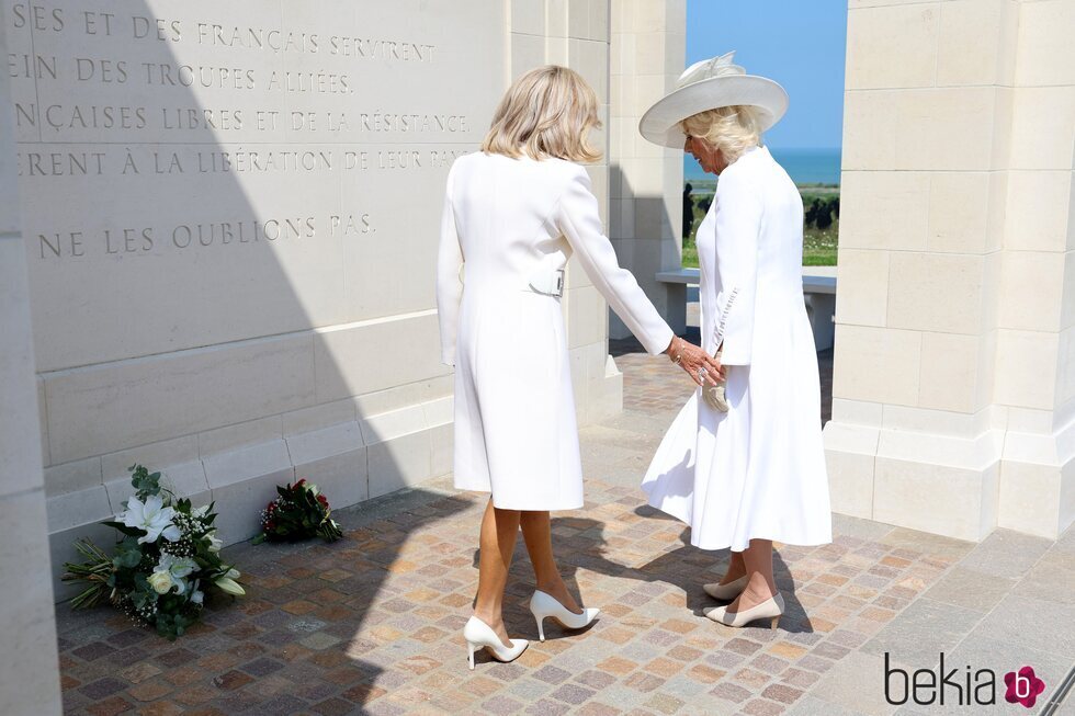 Brigitte Macron tratando de coger de la mano a la Reina Camilla en el 80 aniversario del Desembarco de Normandía