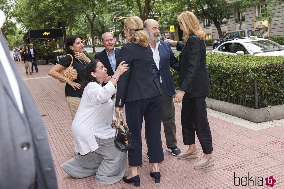 La mujer de Antonio Resines hace una reverencia a la Infanta Elena mientras la Infanta Cristina saluda a Antonio Resines en el funeral de la hermana de Lor