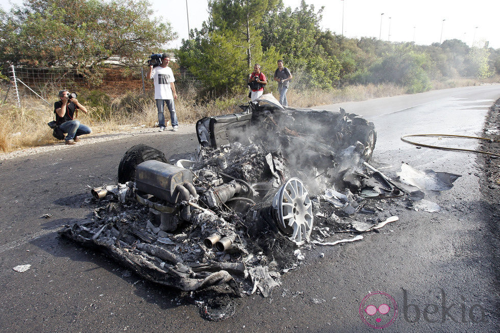 Un bombero echa agua sobre el Ferrari calcinado de Ever Banega