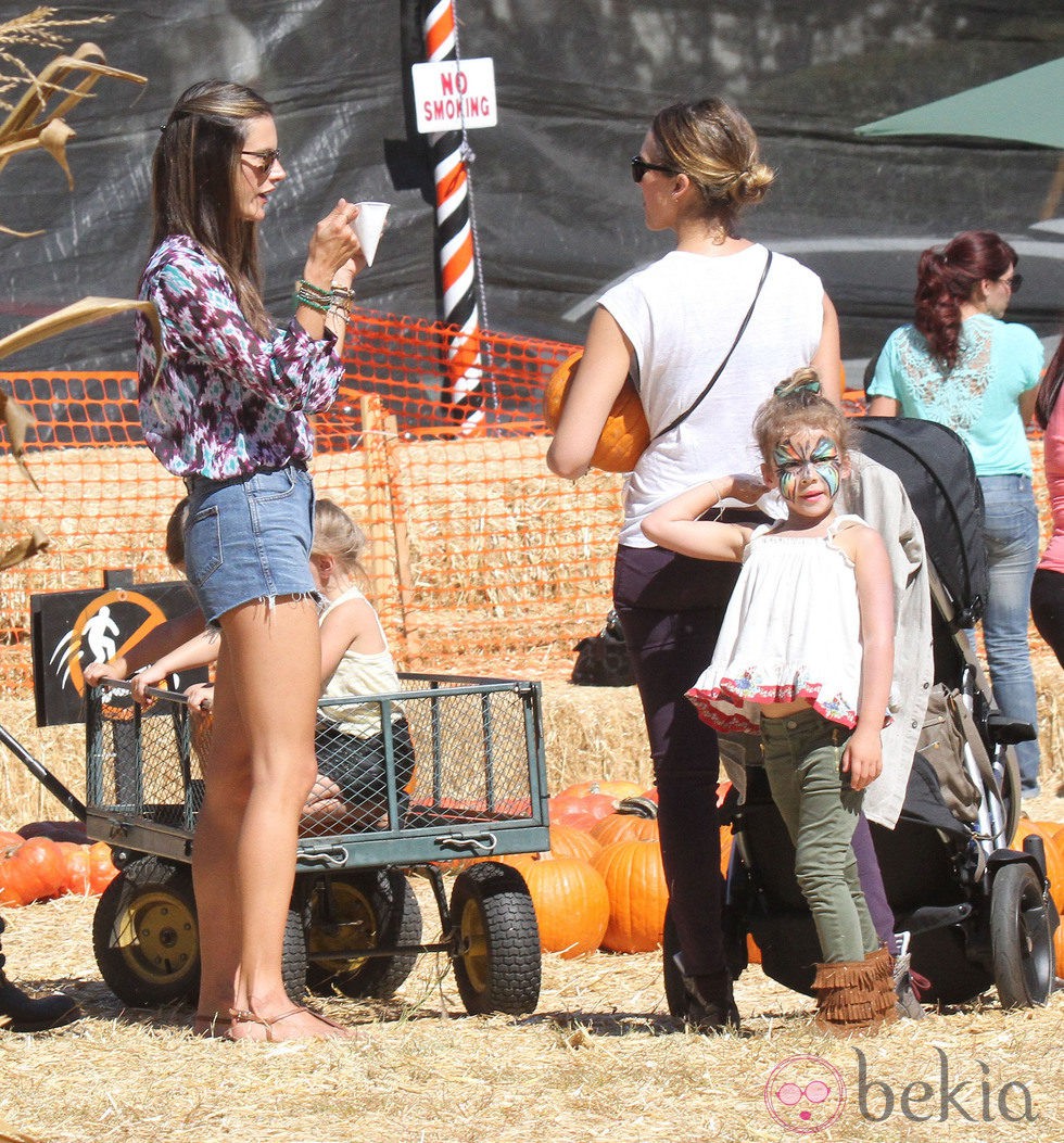 Alessandra Ambrosio y Jessica Alba charlando mientras recogen calabazas para celebrar 'Halloween'