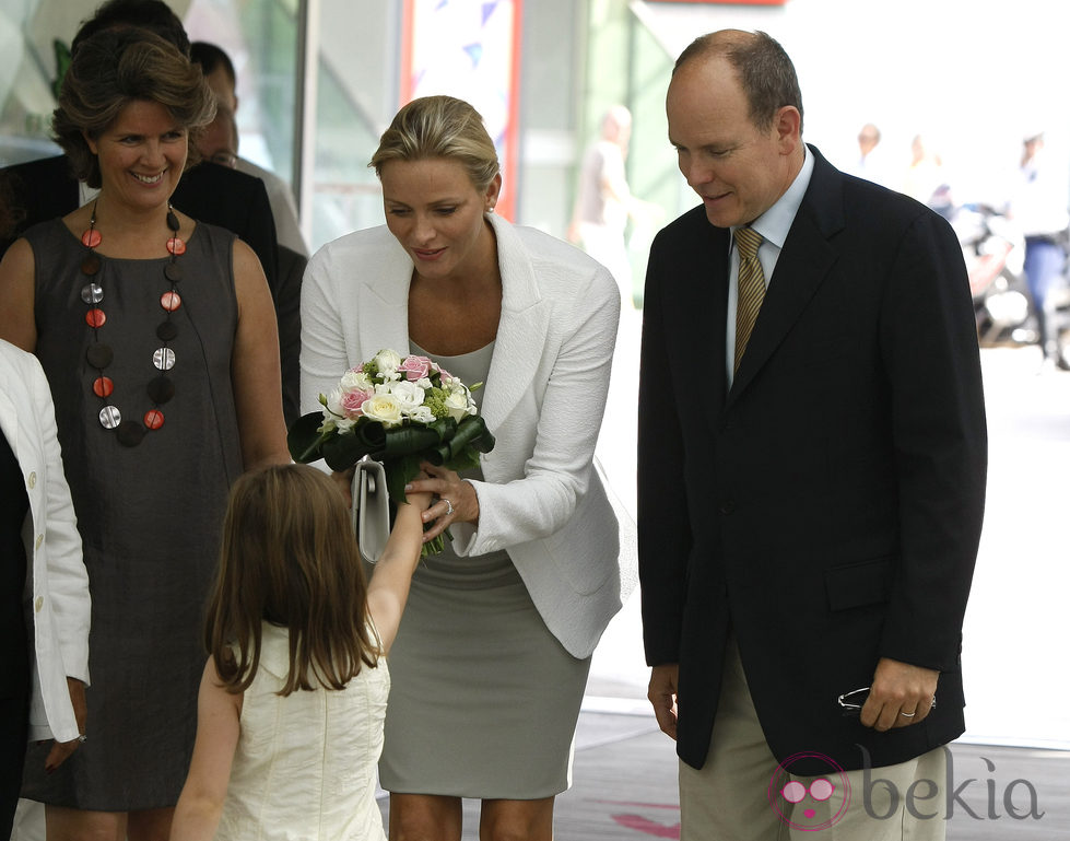 Charlene recibe un ramo de flores bajo la atenta mirada de Alberto de Mónaco