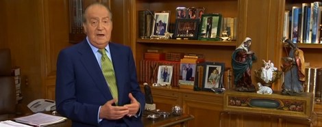 El Rey Juan Carlos, sentado sobre la mesa en su discurso de Navidad 2012