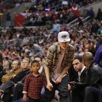 Justin Bieber con un niño de la mano en la NBA